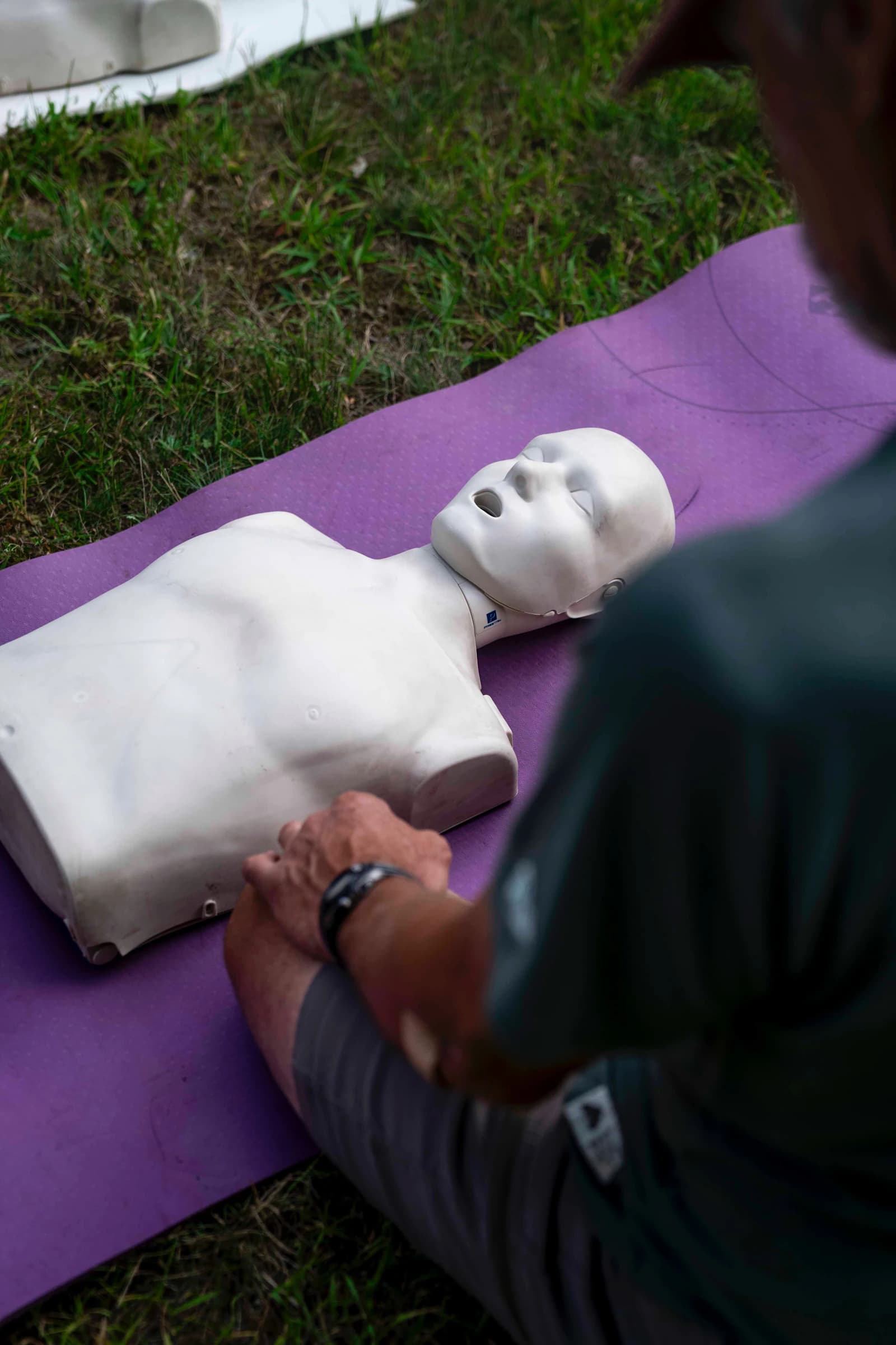 Instructor guiding a student through chest compressions on an adult CPR training mannequin